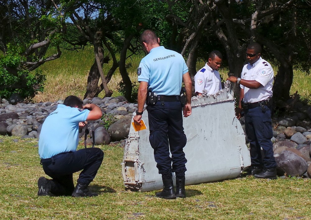French gendarmes and police inspect a large piece of plane debris which was found on the beach in Saint-Andre, on the French Indian Ocean island of La Reunion